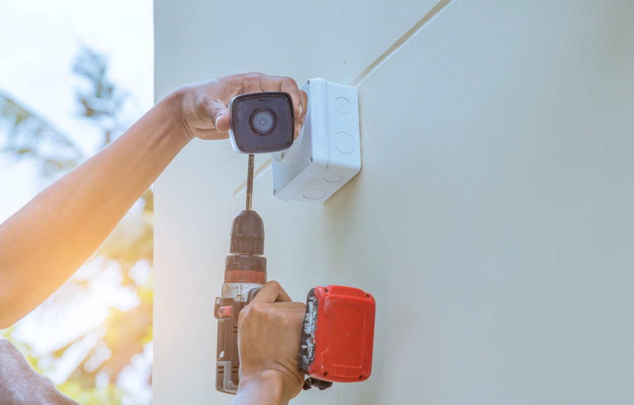guy using a drill to installing a outdoor camera